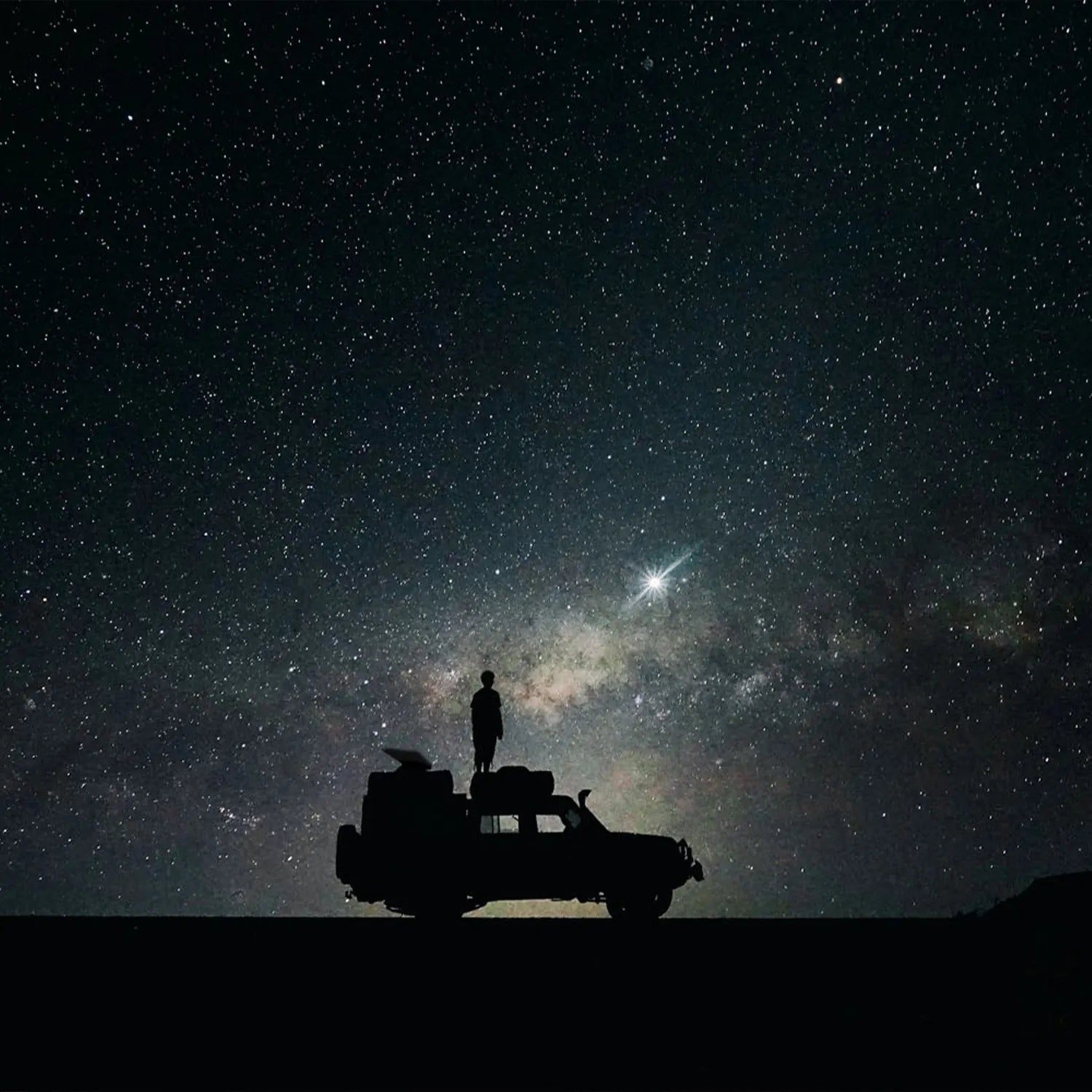Person stargazing beside a Starlink Mini dish and a portable external battery on a dark horizon