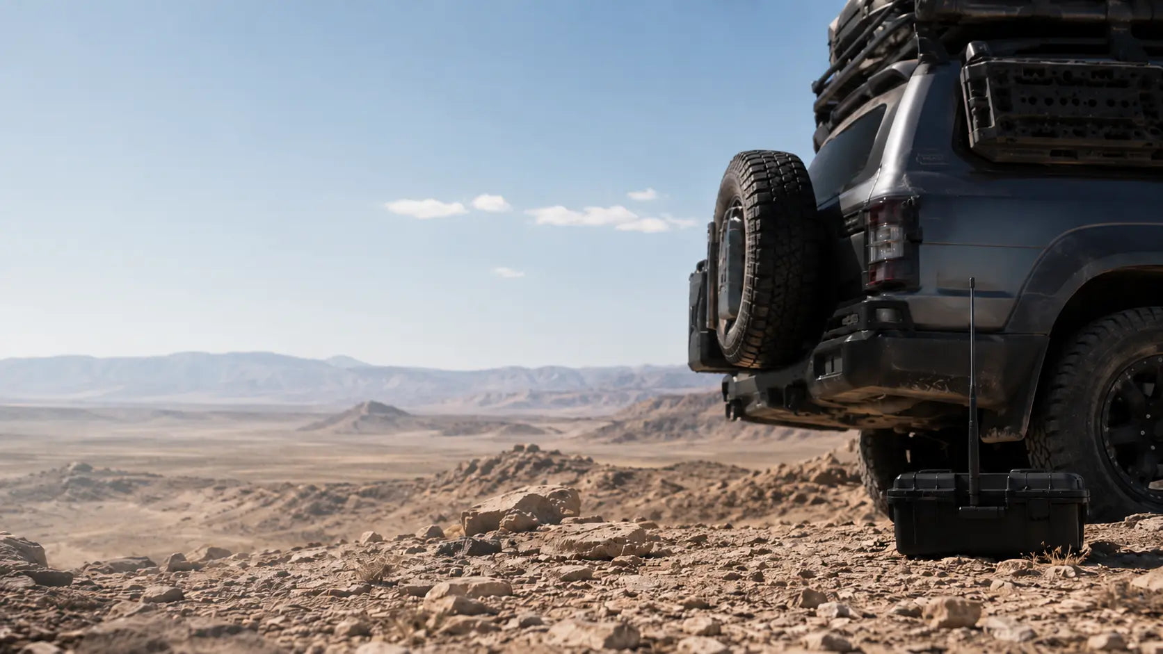 Overlanding vehicle with a portable off-grid communication setup in a remote desert landscape.